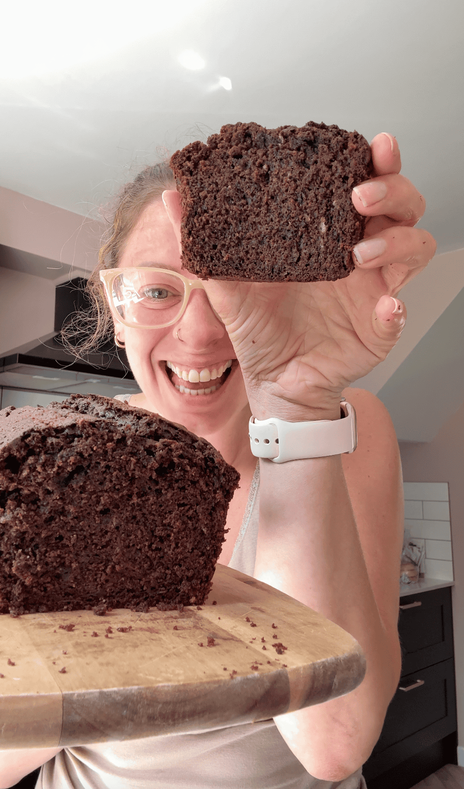 Author Sarah Howells holding up a slice of chocolate courgette cake.