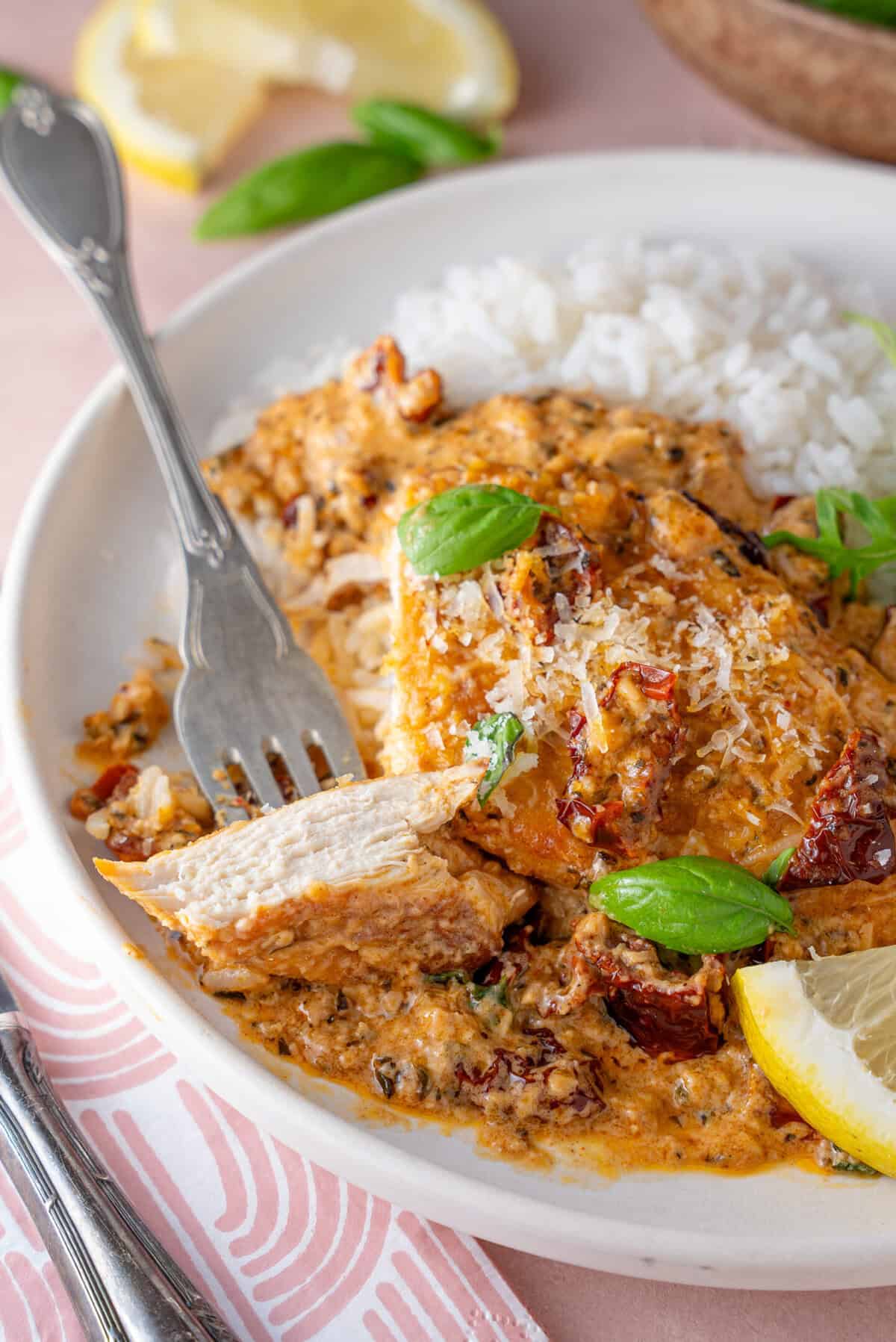 A plate of Marry Me Chicken with a piece of chicken cut off.
