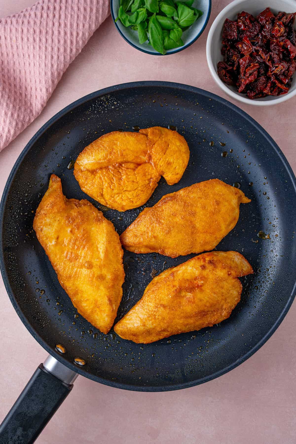 Fry the chicken breasts in the pan until browned.