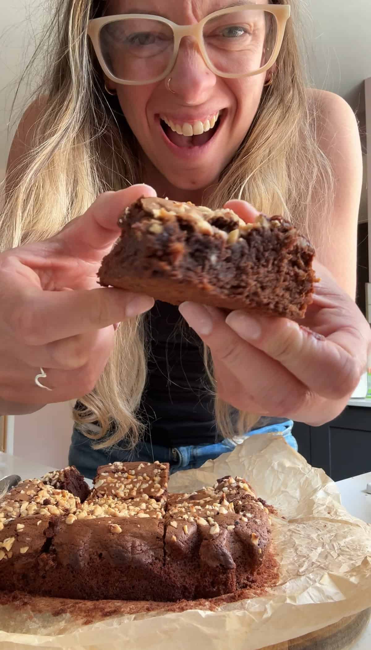 Author Sarah Howells holding a piece of Nutella brownie and smiling.