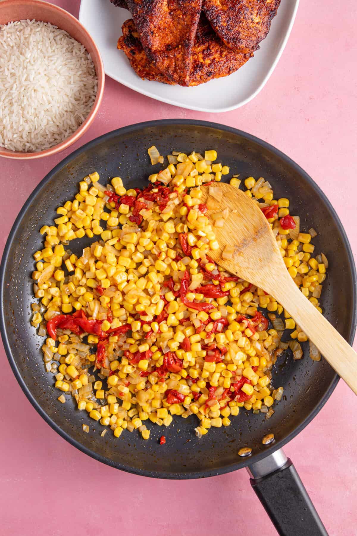 A pan with onion, sweetcorn and red peppers.