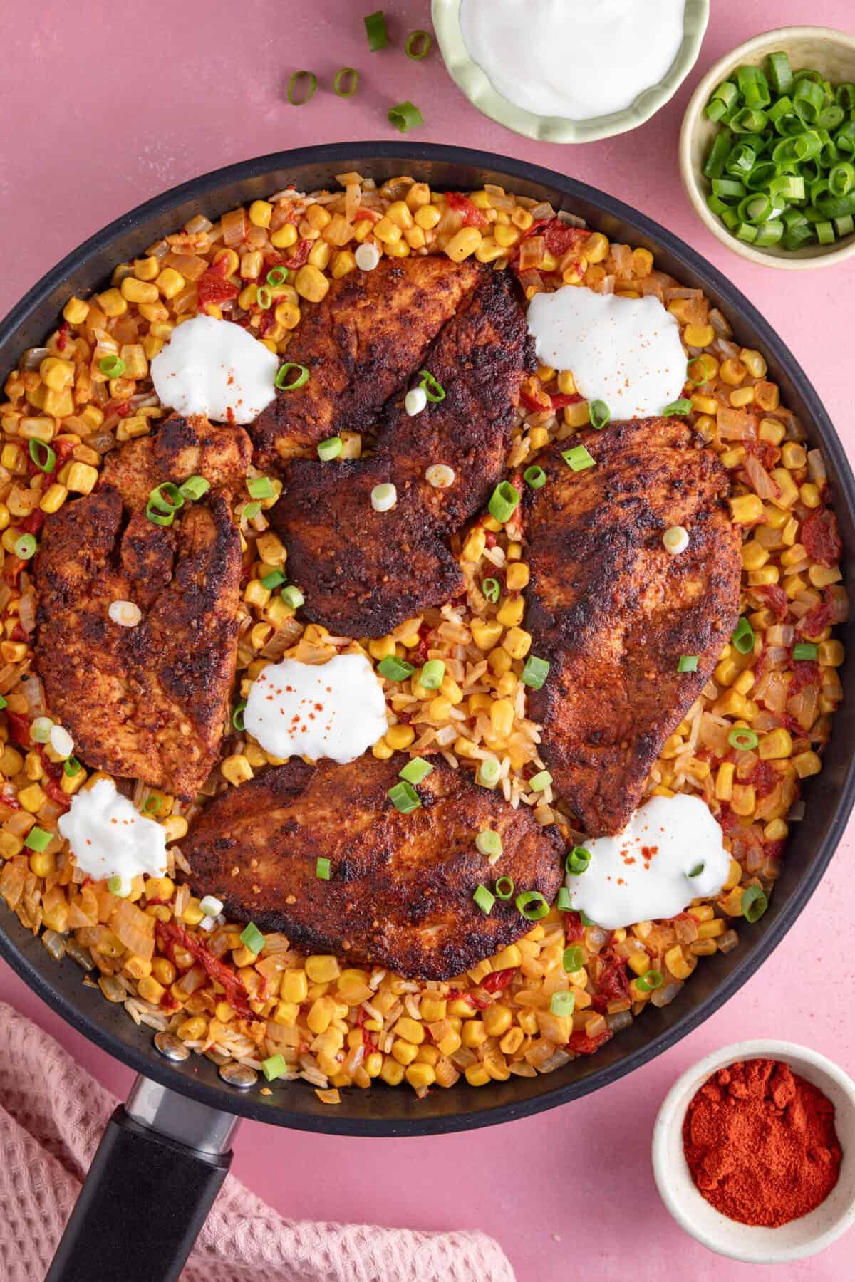 A one-pan bowl of cajun chicken and spicy rice with soured cream on top.