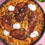 A one-pan bowl of cajun chicken and spicy rice with soured cream on top.