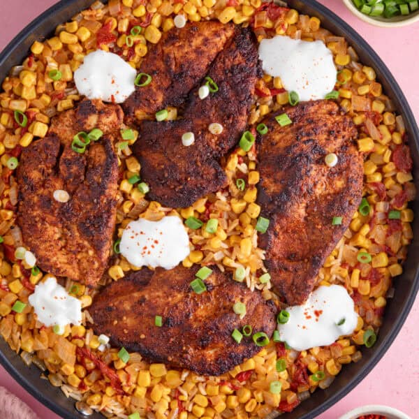 A one-pan bowl of cajun chicken and spicy rice with soured cream on top.
