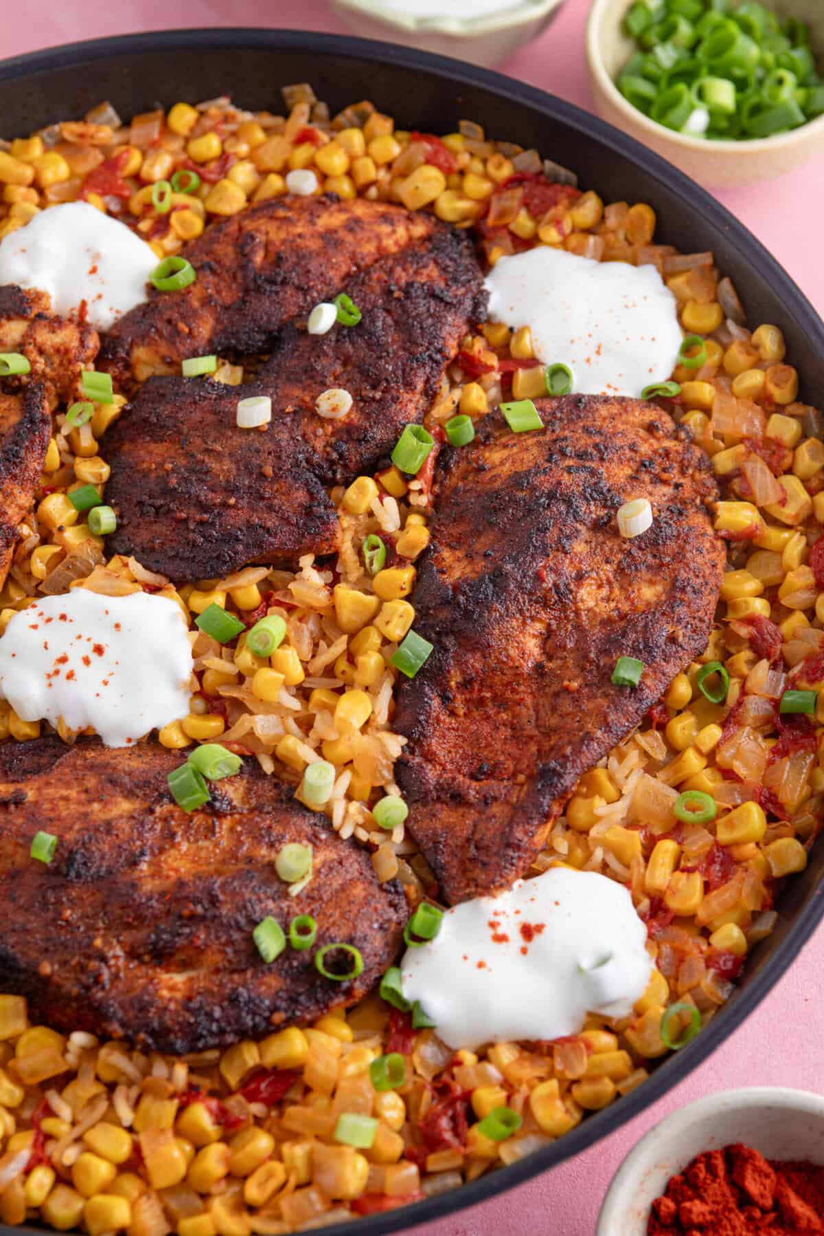 A one-pan bowl of cajun chicken and spicy rice with soured cream on top.