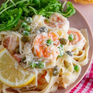 A plate of creamy prawn pasta with lemon and capers.