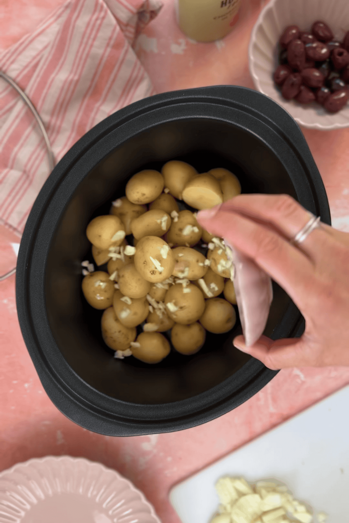 Adding the potatoes onions and garlic to a pan.
