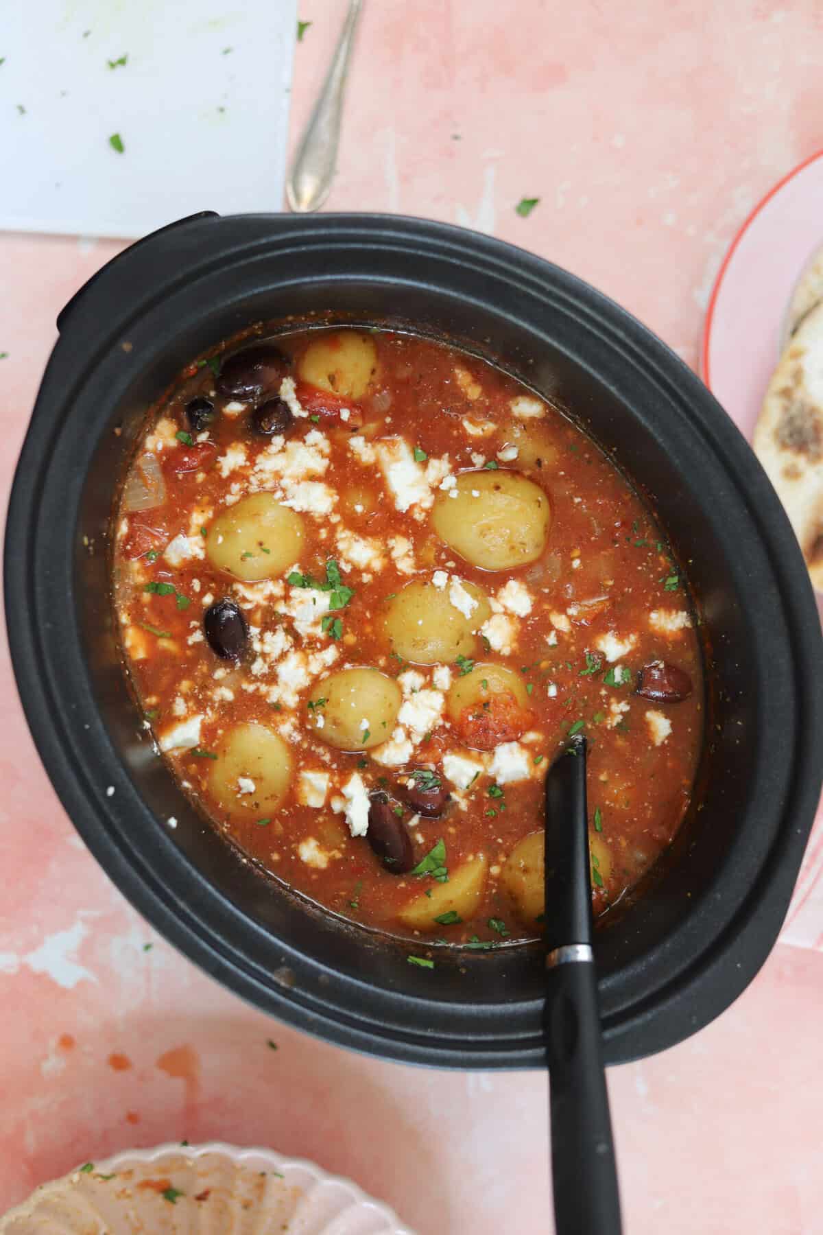 A slow cooker pan filled with Greek potato stew.