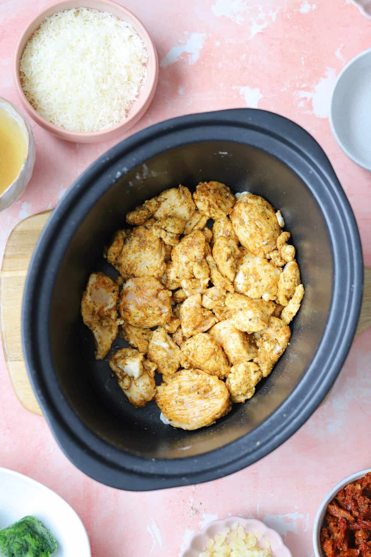 Process shot of slow cooker tuscan chicken recipe showing the browned chicken in the slow cooker.