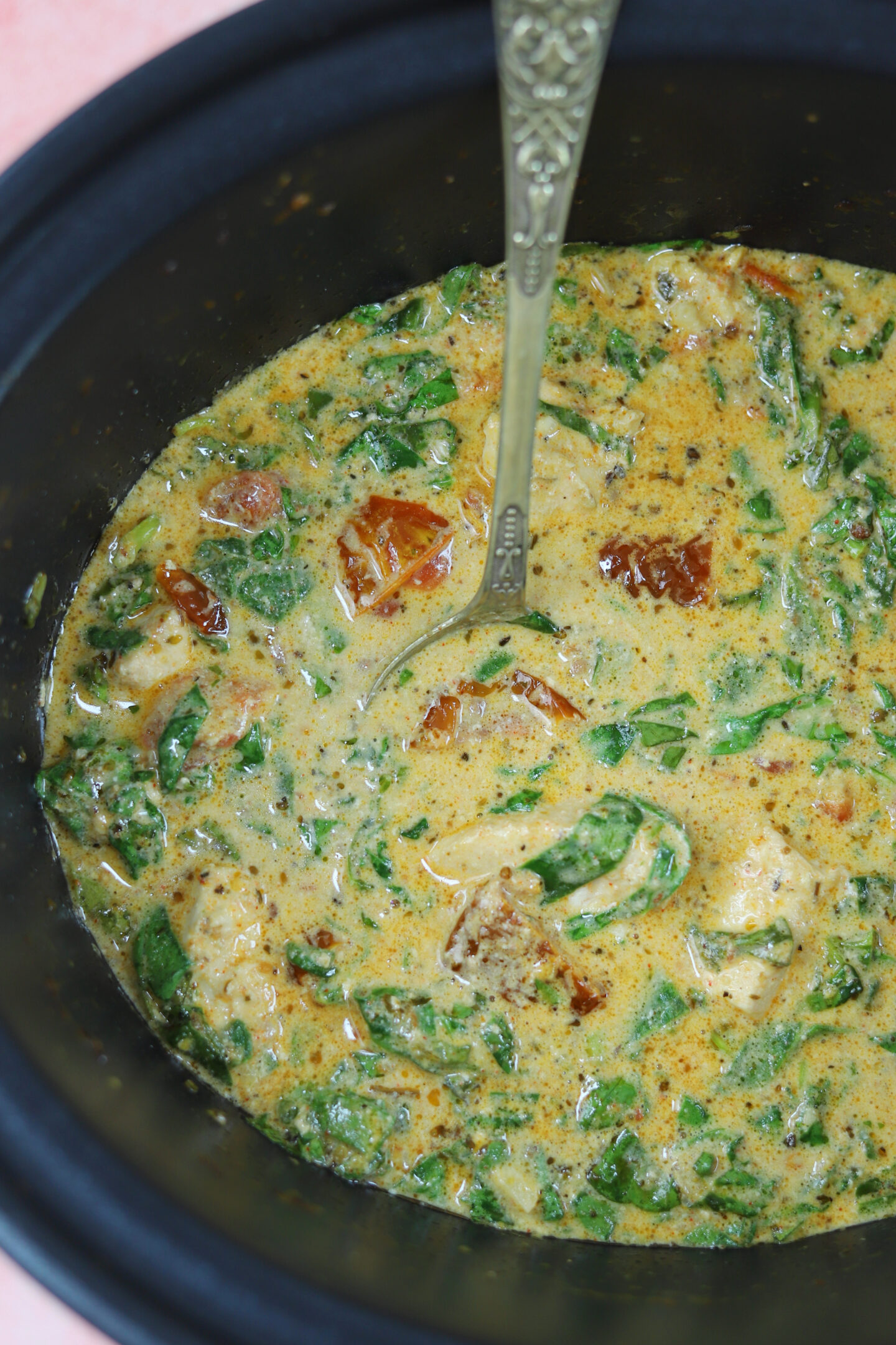 Creamy tuscan chicken in a slow cooker pan.