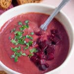 A bowl of beetroot soup with a spoon in it.