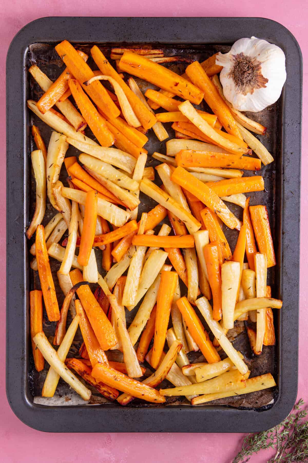Roasted carrots, parsnips and garlic on a tray.