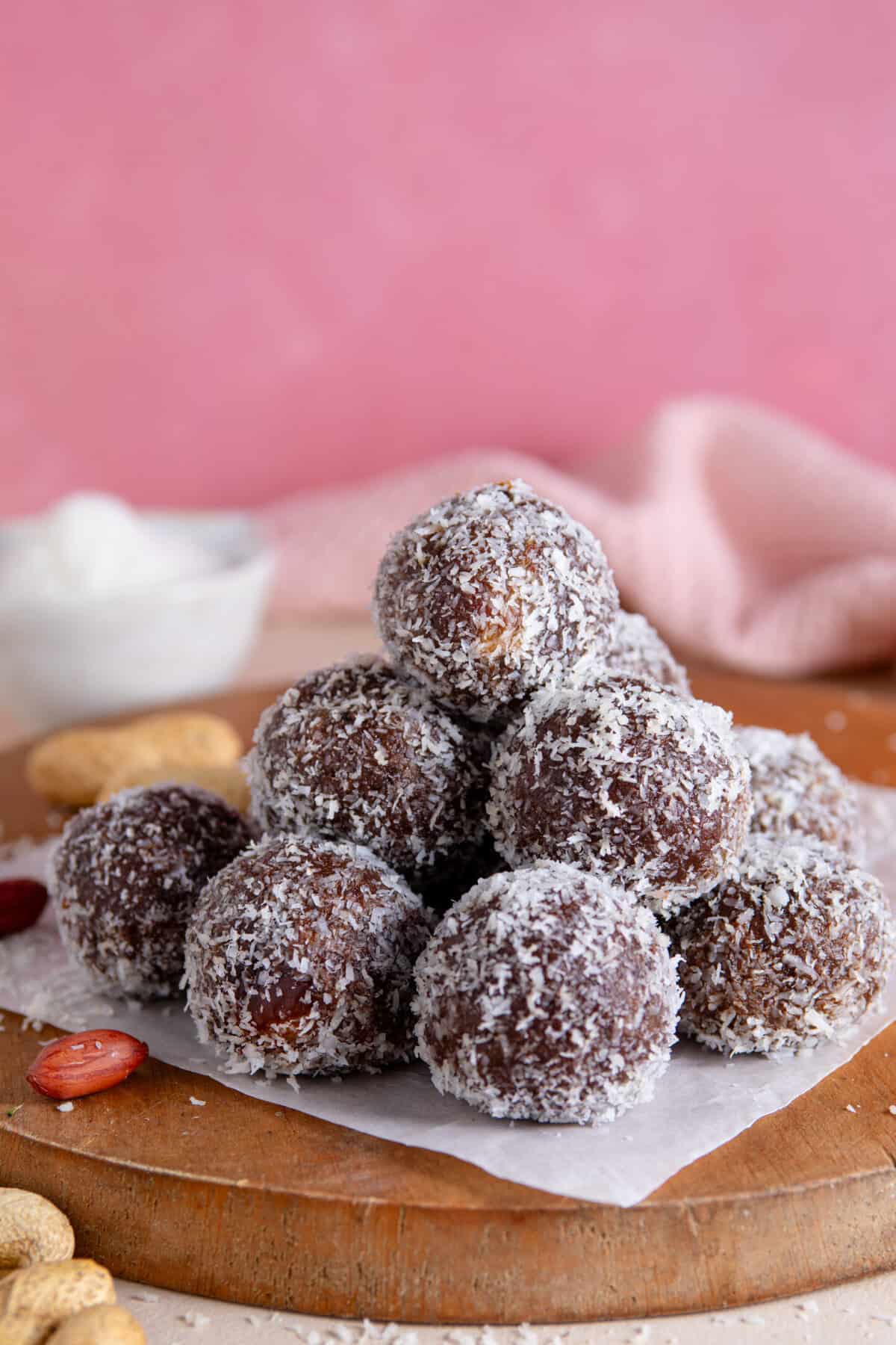 A pyramid of date energy balls on a wooden chopping board.