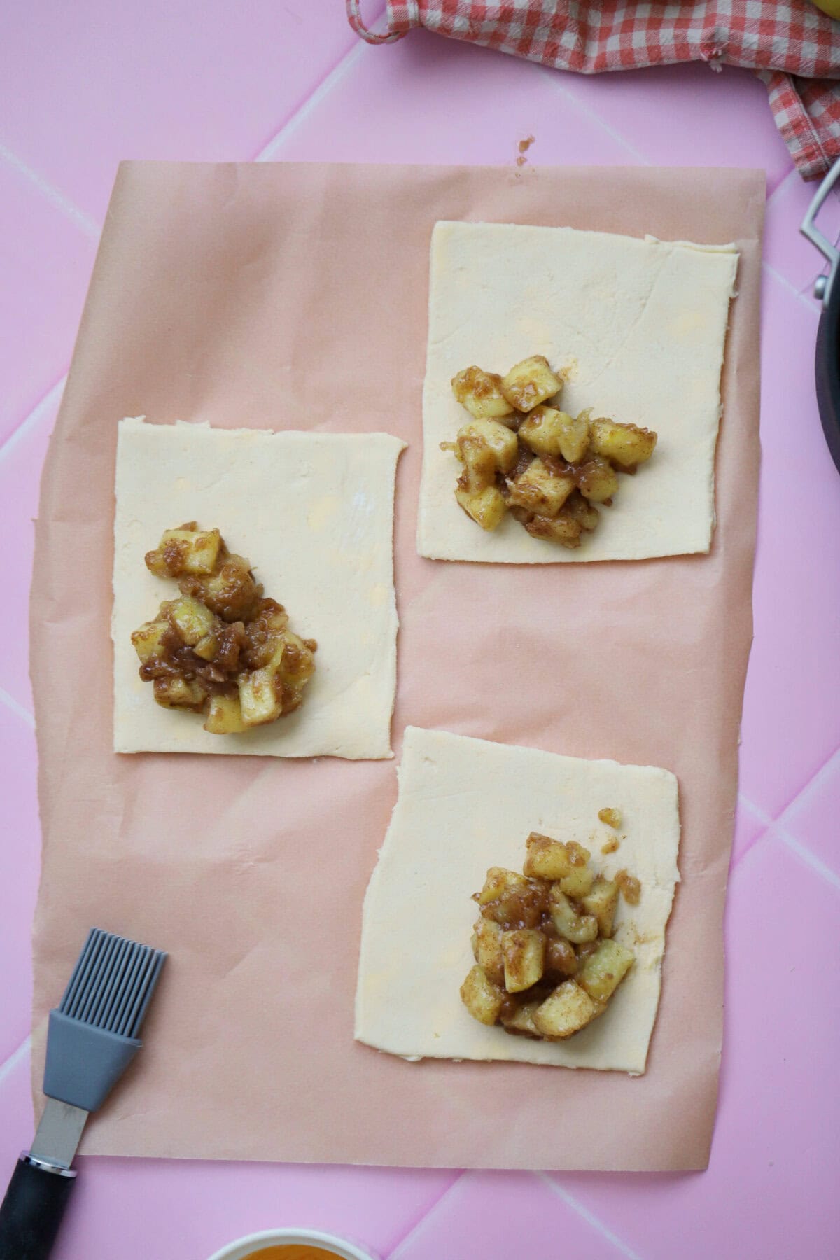 Place the apple turnover filling on the puff pastry sheets and brush the border with egg.