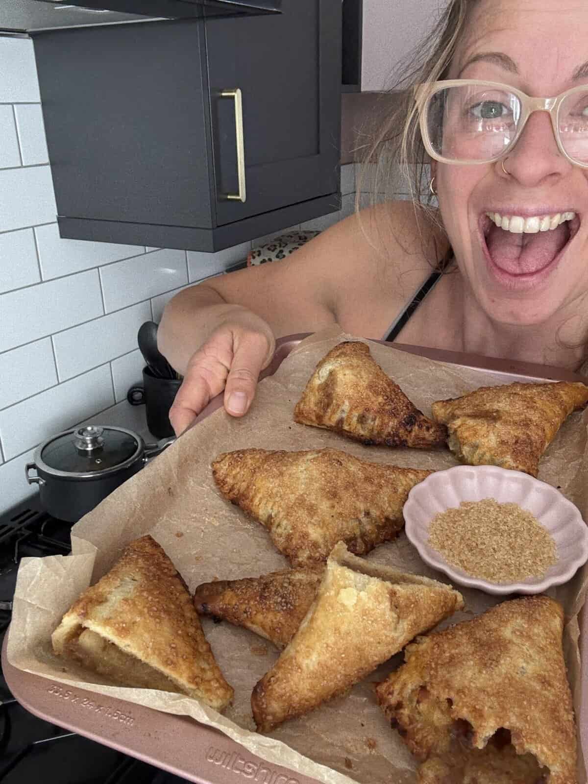 Post author Sarah Howells holding a tray of gluten free apple turnovers.