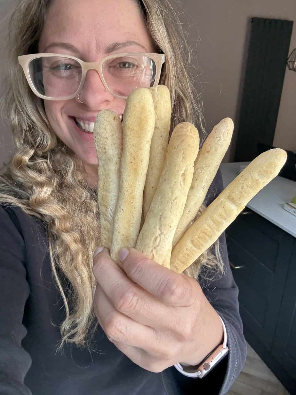 Author Sarah Howells holding up a bouquet of gluten free breadsticks.