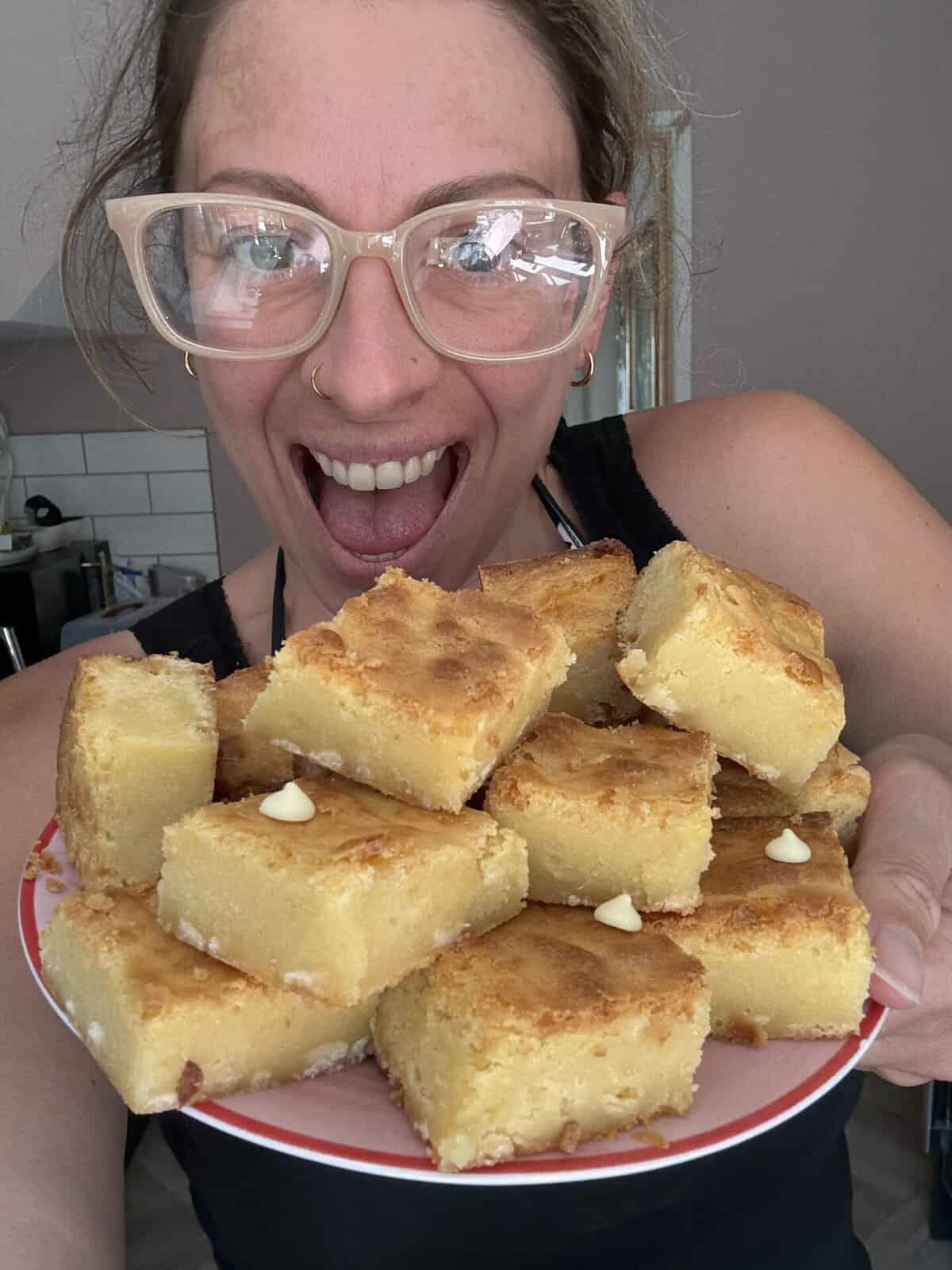 Author Sarah Howells holding a plate of white chocolate brownies.