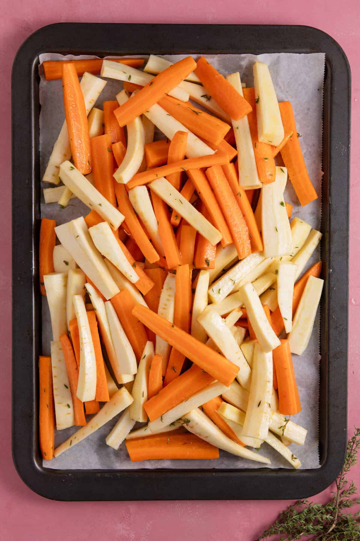 Carrots and parsnips on a baking tray before roasting.