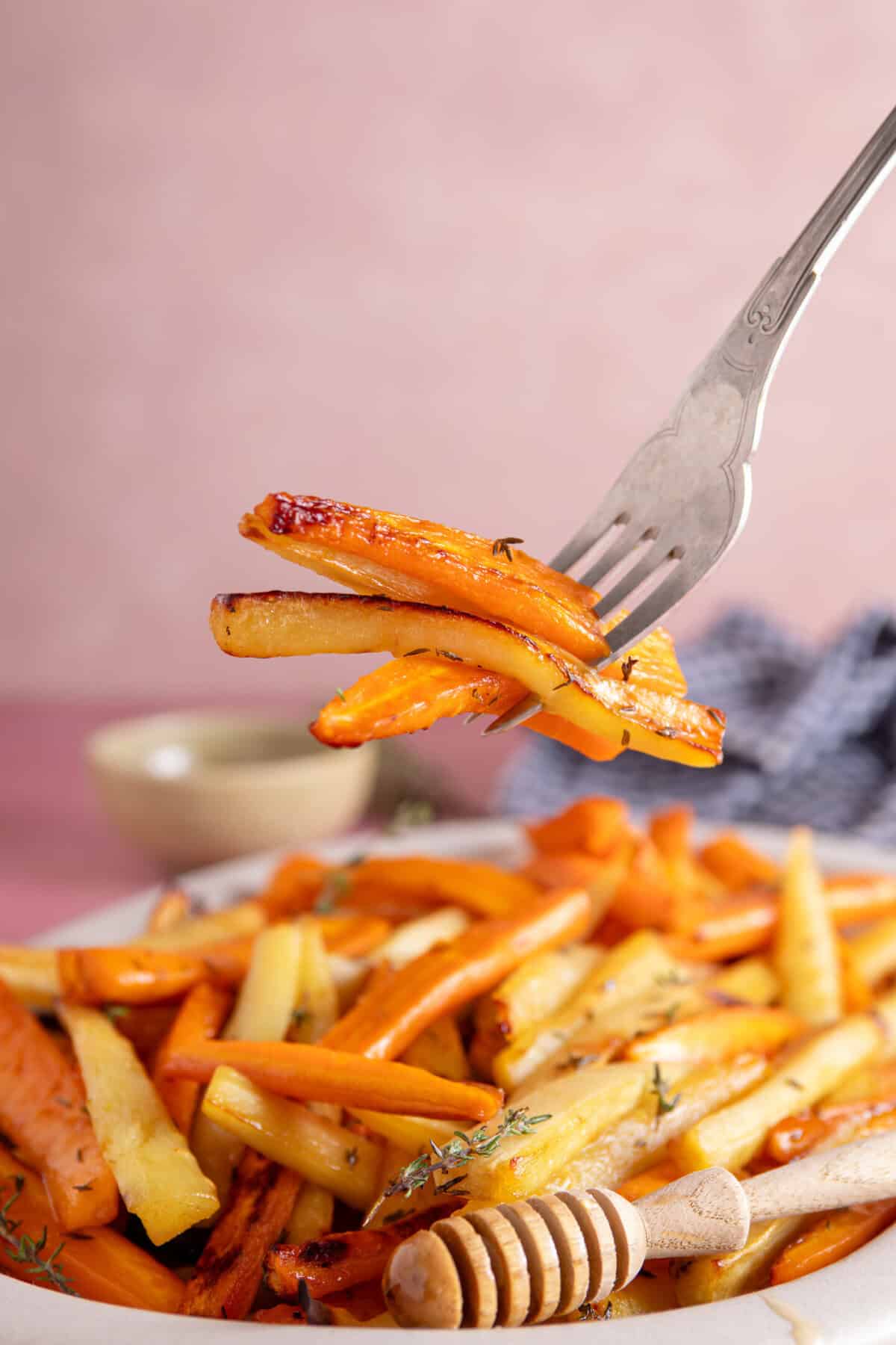 Fork holding up some roasted carrots and parsnips.