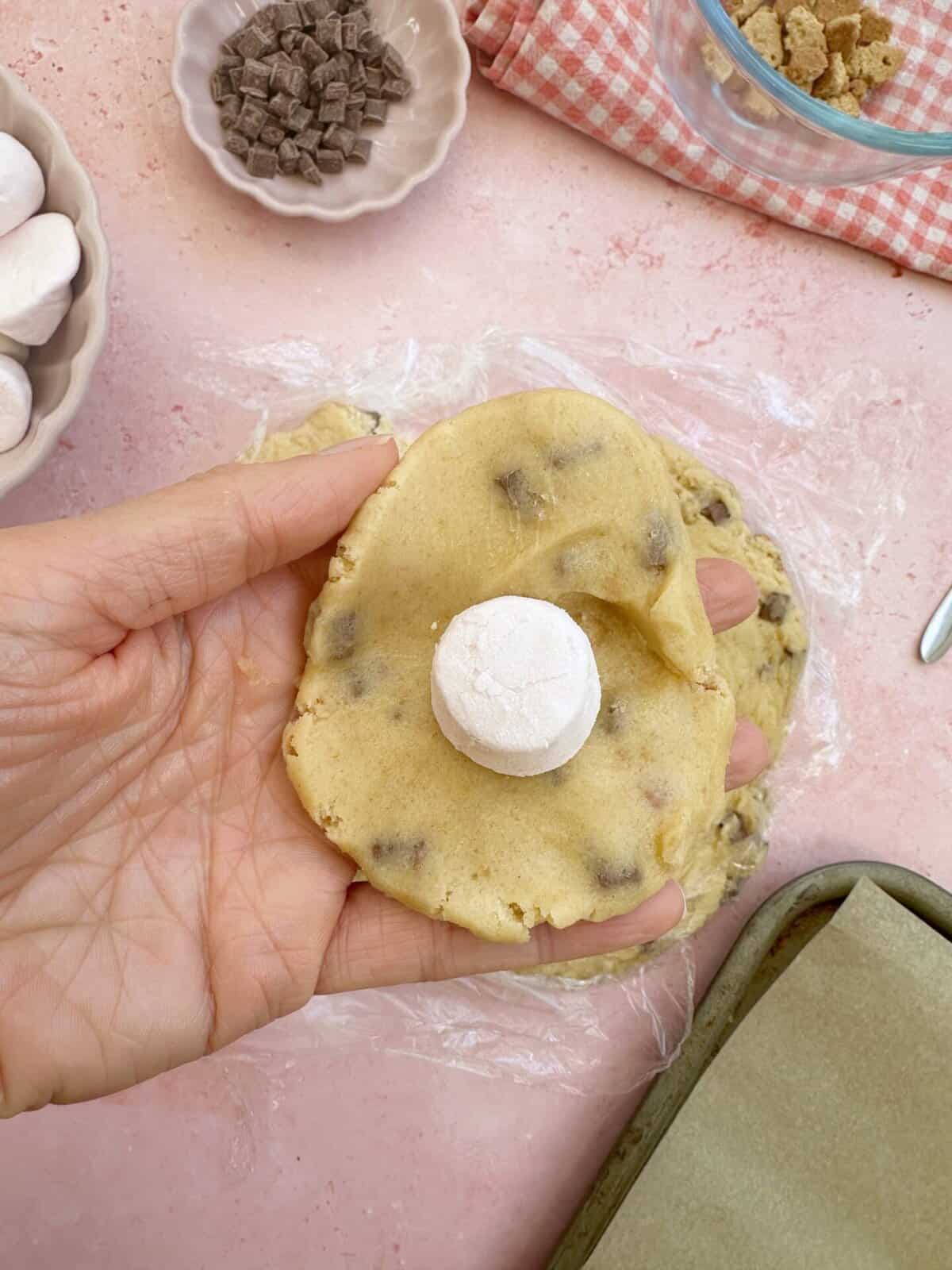 Break off a portion of cookie dough and place a marshmallow in the centre.