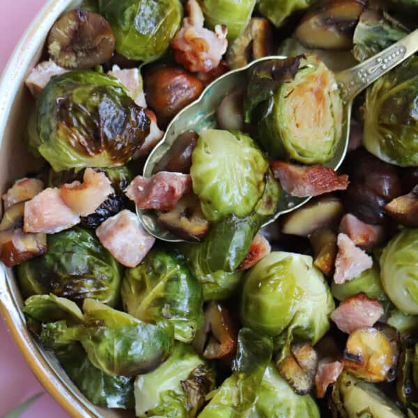 A bowl of brussels sprouts with chestnuts and bacon.