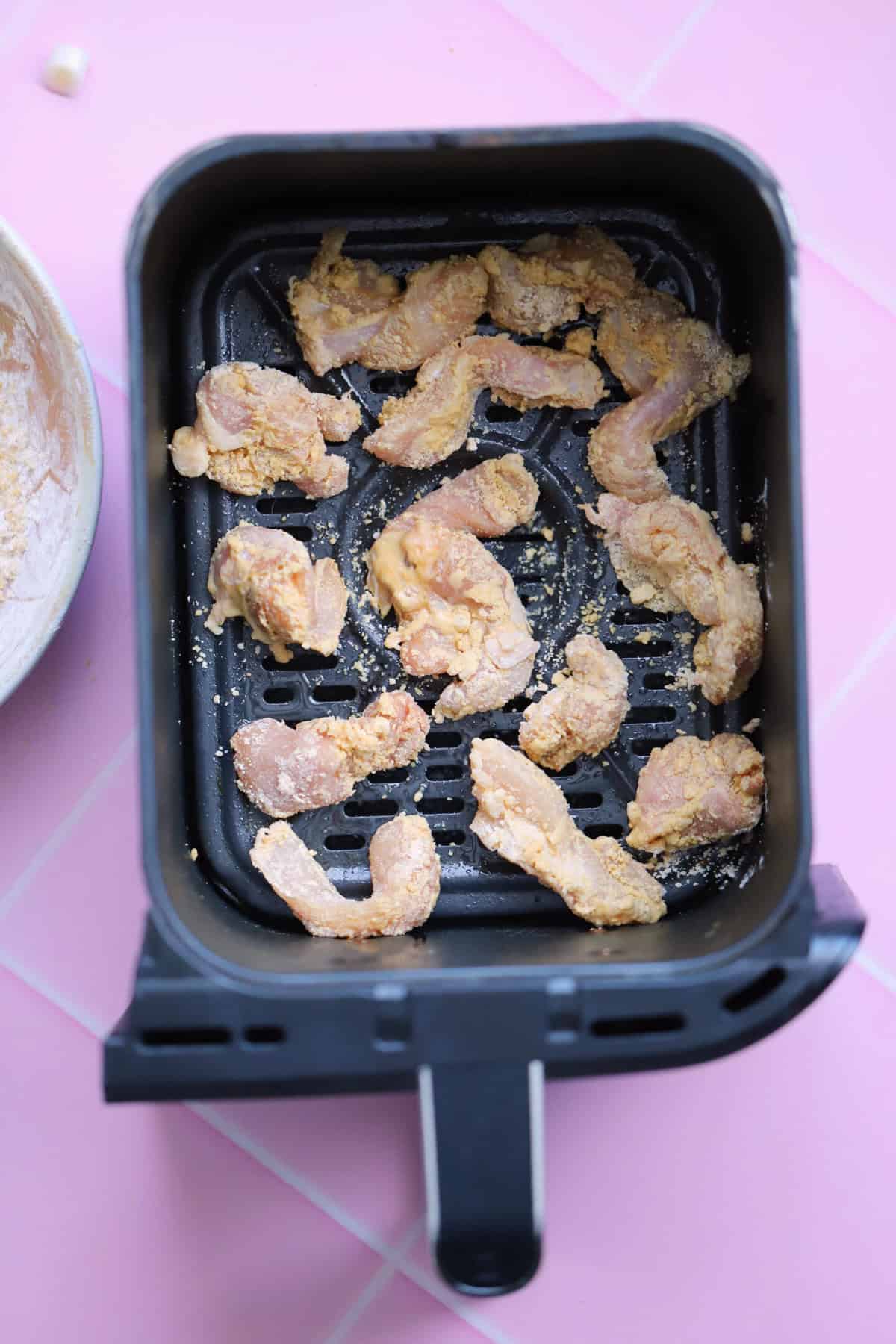 Add the chicken pieces to the air fryer basket with space between them.