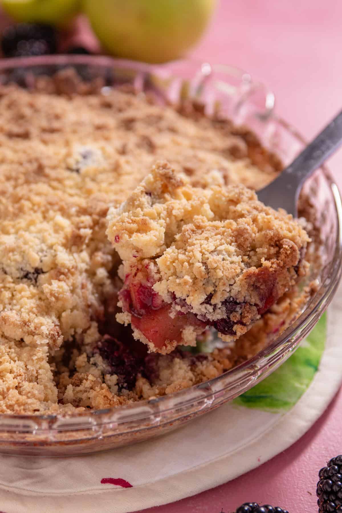 A gluten free apple and blackberry crumble with a spoonful taken out.