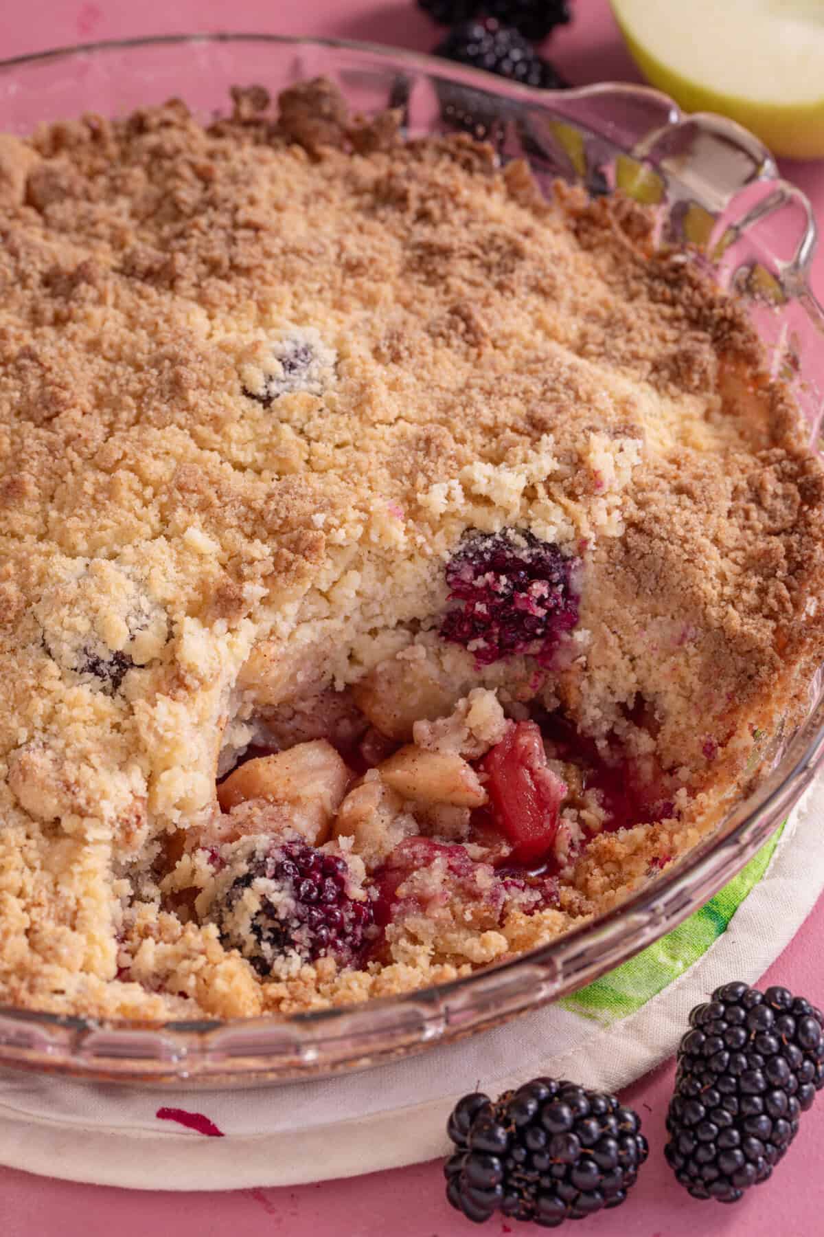 A gluten free apple and blackberry crumble with a spoonful taken out.