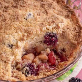 A gluten free apple and blackberry crumble with a spoonful taken out.