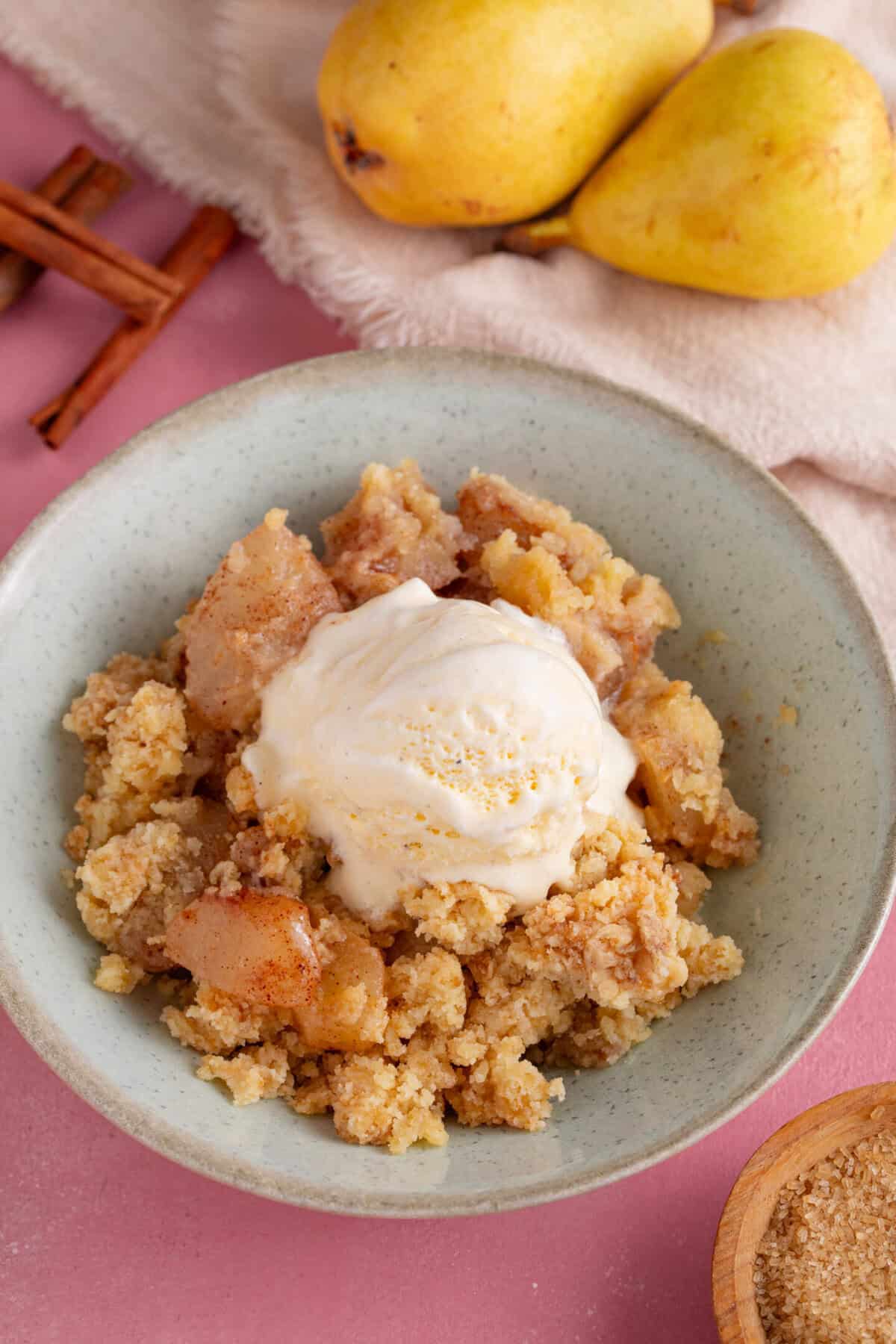 A bowl of spiced pear crumble with a scoop of ice-cream on top.