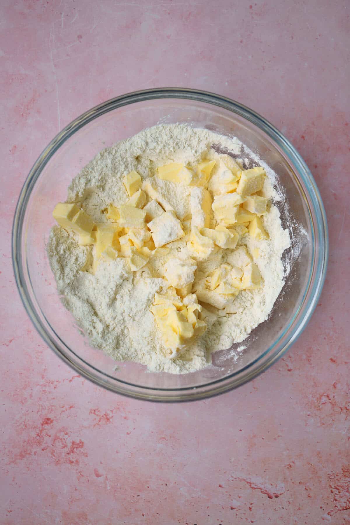 Add the cold cubes of butter to the dry ingredients in a mixing bowl.