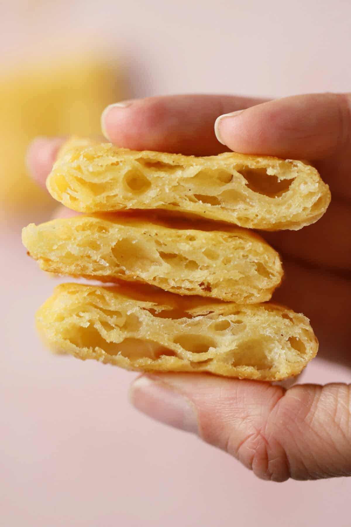Hand holding flaky layers of gluten free puff pastry.
