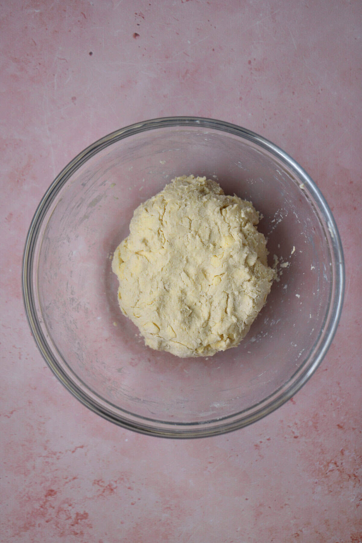 A ball of gluten free puff pastry dough in a glass bowl.