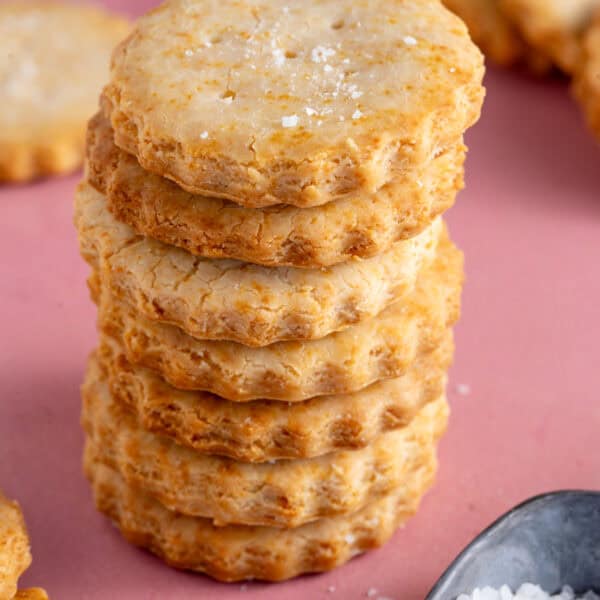 A stack of gluten free Ritz crackers on a pink backdrop.