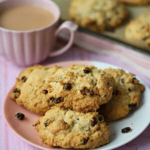 A plate of gluten free rock cakes with a cup of tea behind.