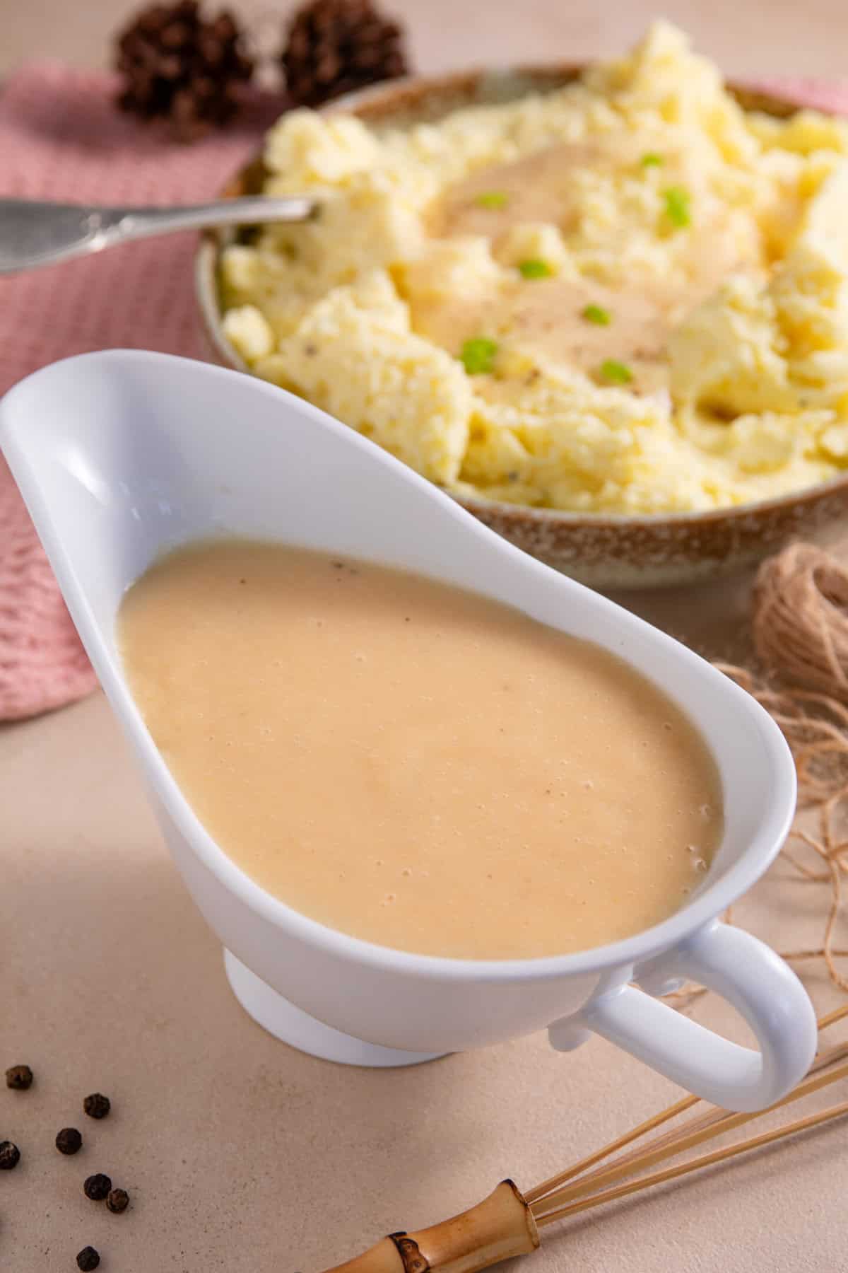 A jug of miso gravy with a bowl of mashed potato behind.