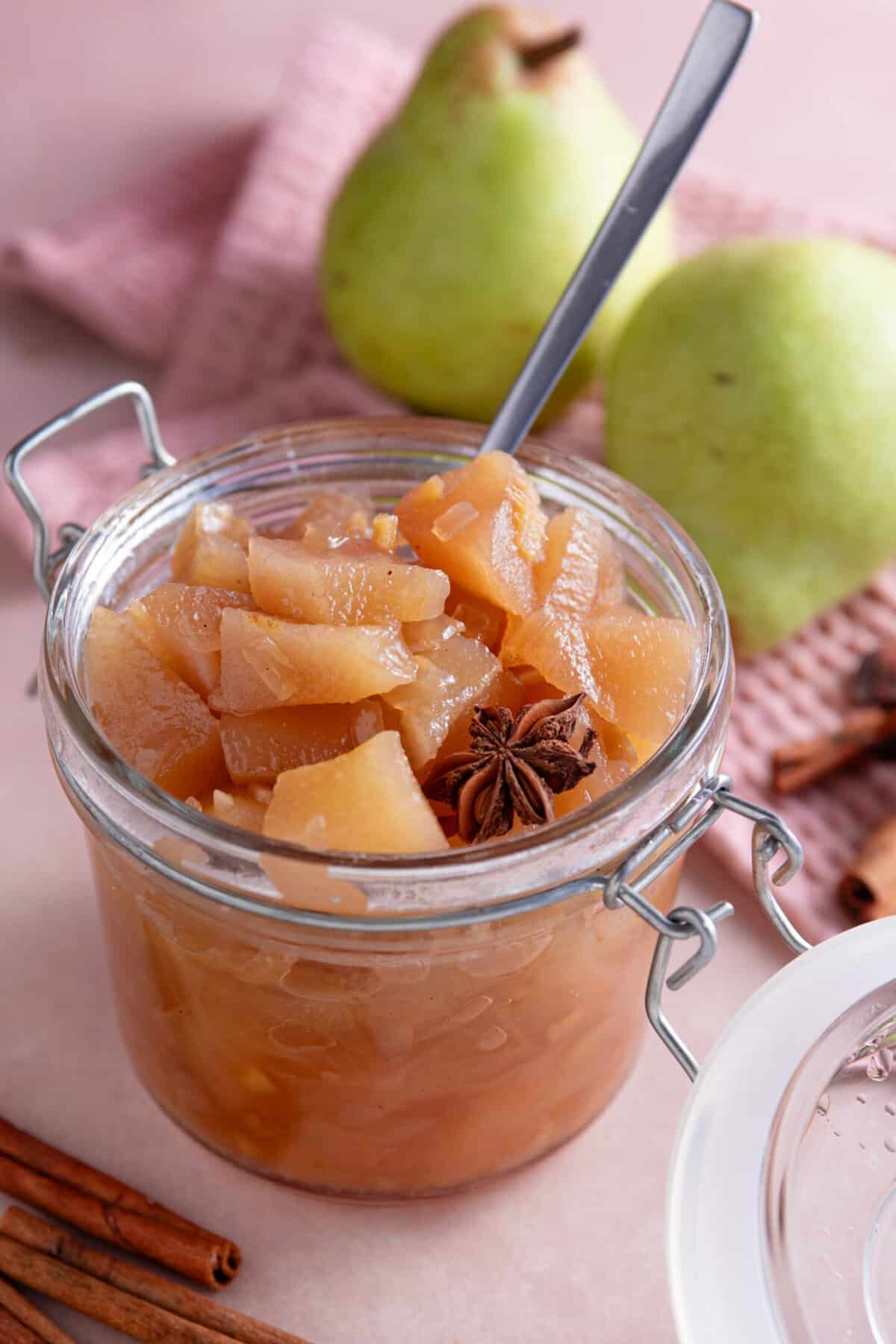 A jar of pear chutney with a star anise and a spoon.