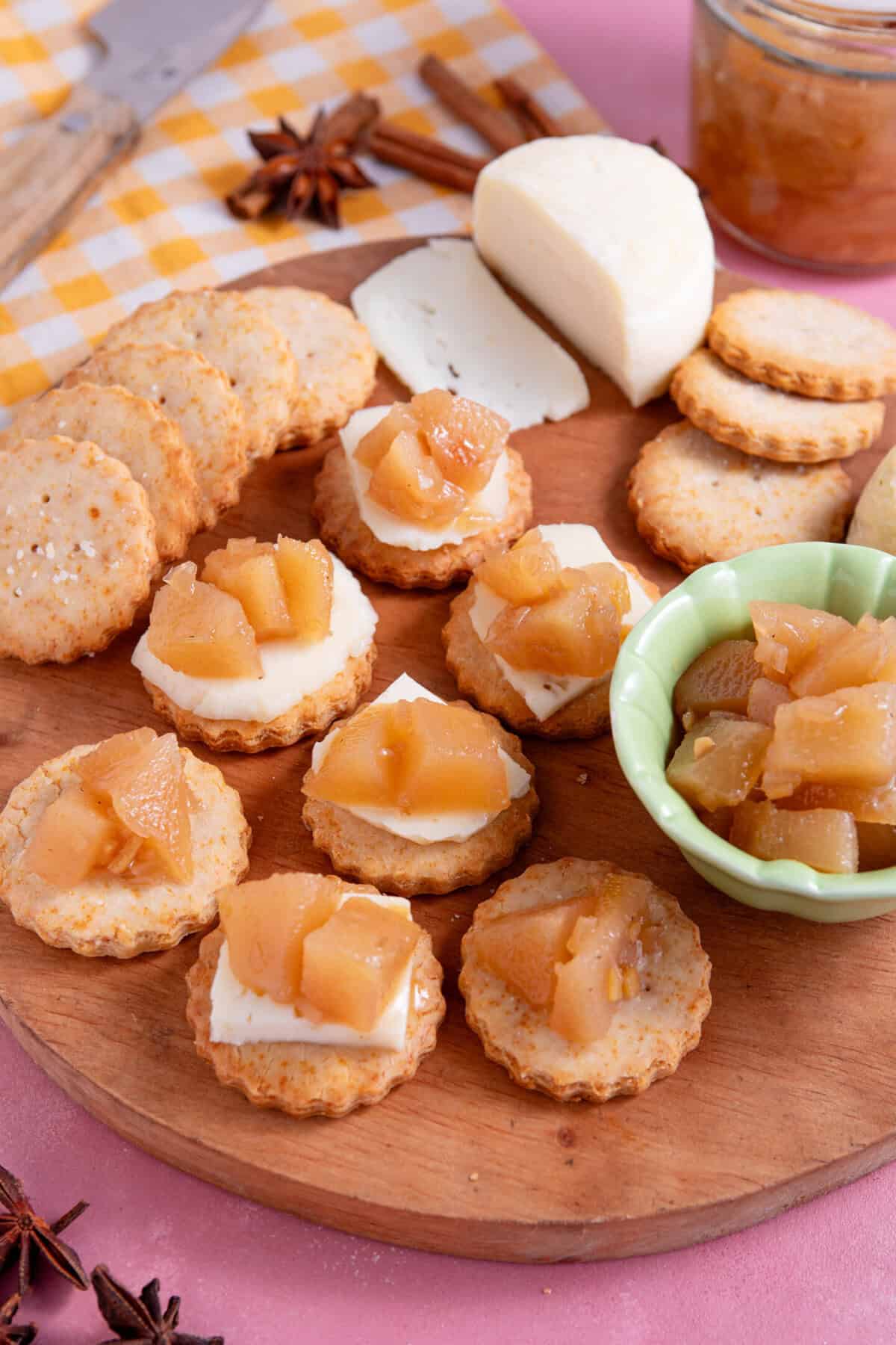 A board of crackers and cheese topped with pear chutney.