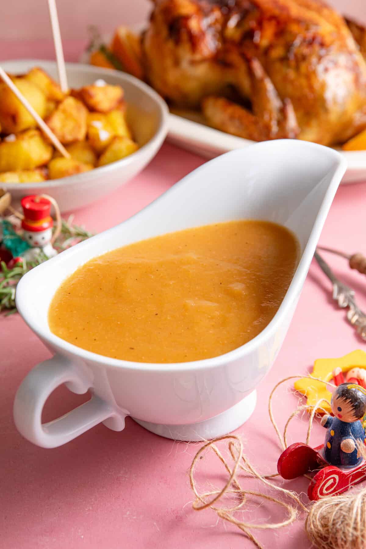 A jug of gluten free Christmas gravy on a dinner spread.
