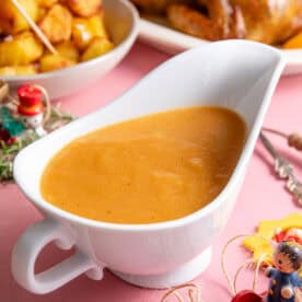 A jug of gluten free Christmas gravy on a dinner spread.