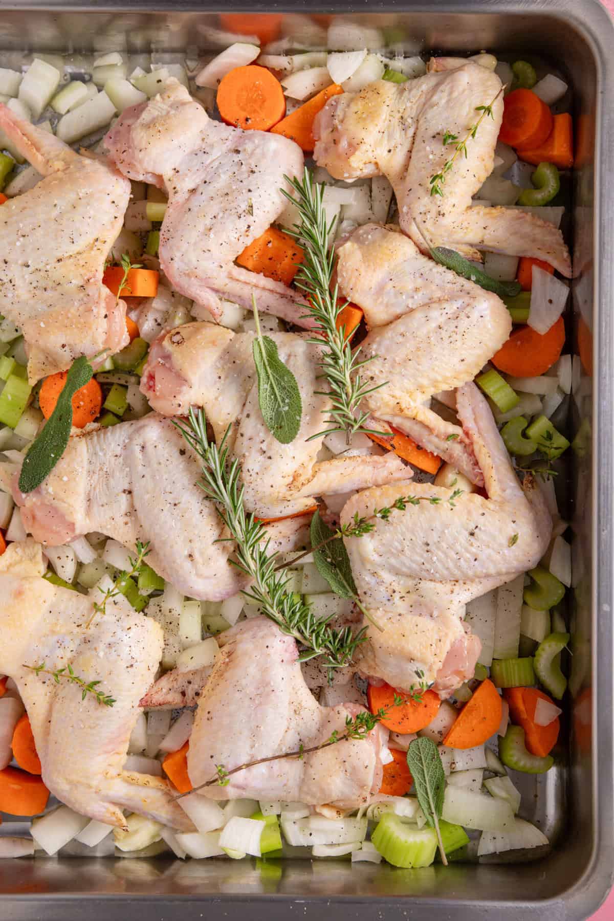 Arrange the chicken wings, veg and herbs in a roasting tin.