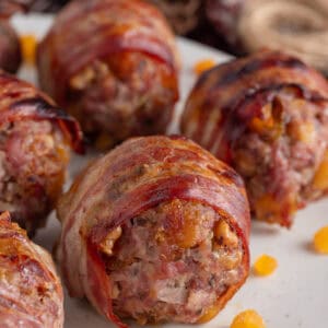 Close up of a plate of bacon-wrapped gluten free stuffing balls with chopped apricots.