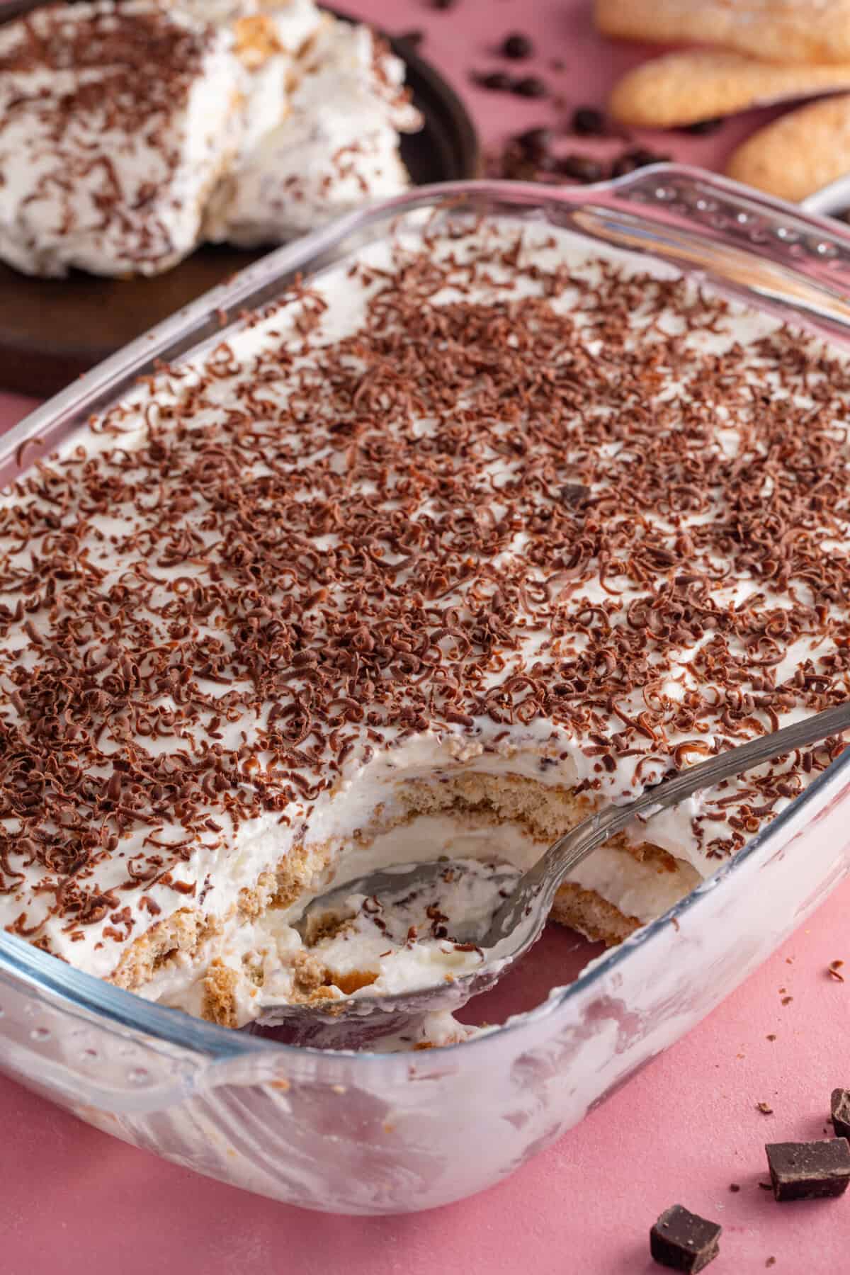 A gluten free tiramisu in a glass dish with a portion removed.