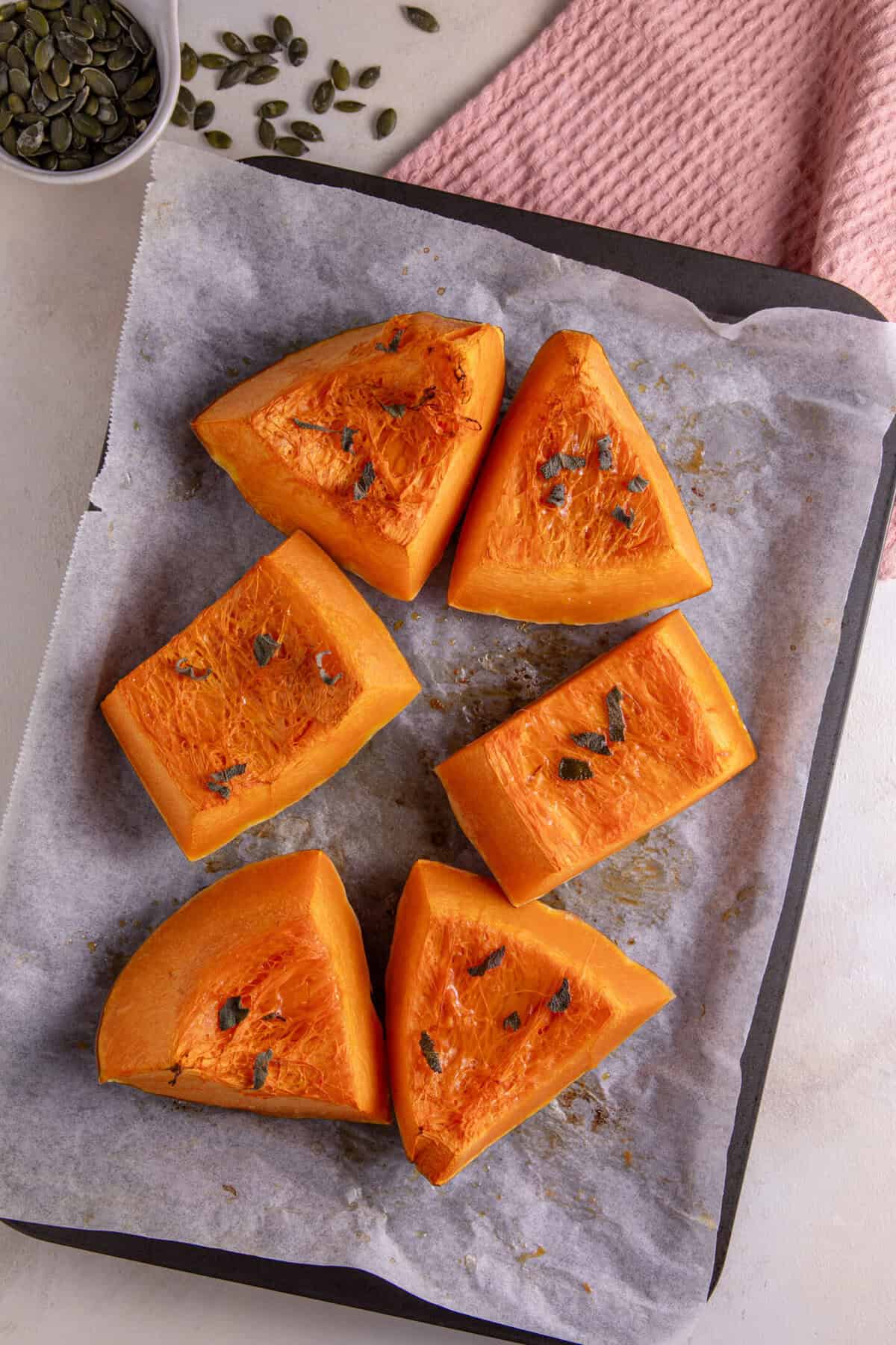 Roasted pumpkin cut into wedges and scattered with sage leaves and chilli oil.