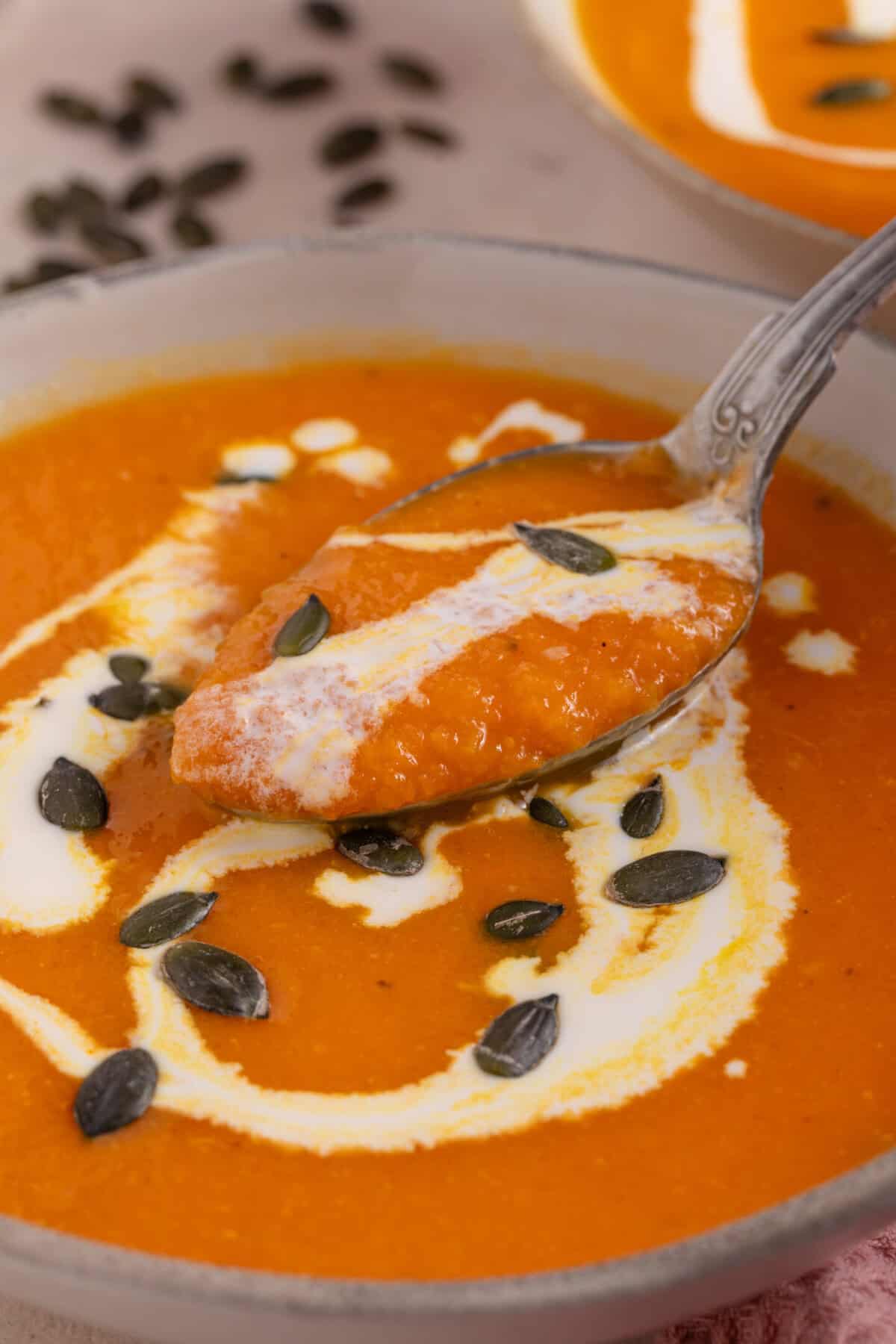 A spoonful of roasted pumpkin soup with a swirl of cream.