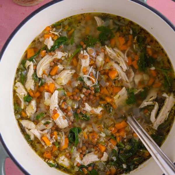 A pan of chicken and lentil soup with a side of gluten free bread.