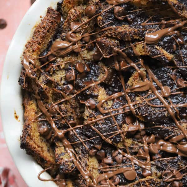 Close up of a chocolate bread and butter pudding with lashings of melted chocolate on top.
