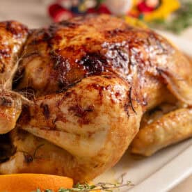A Christmas glazed roast chicken on a serving plate.