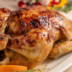 A Christmas glazed roast chicken on a serving plate.