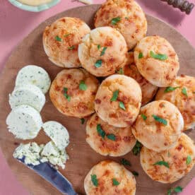 A board of gluten free doughballs with cheese and aioli on the side.